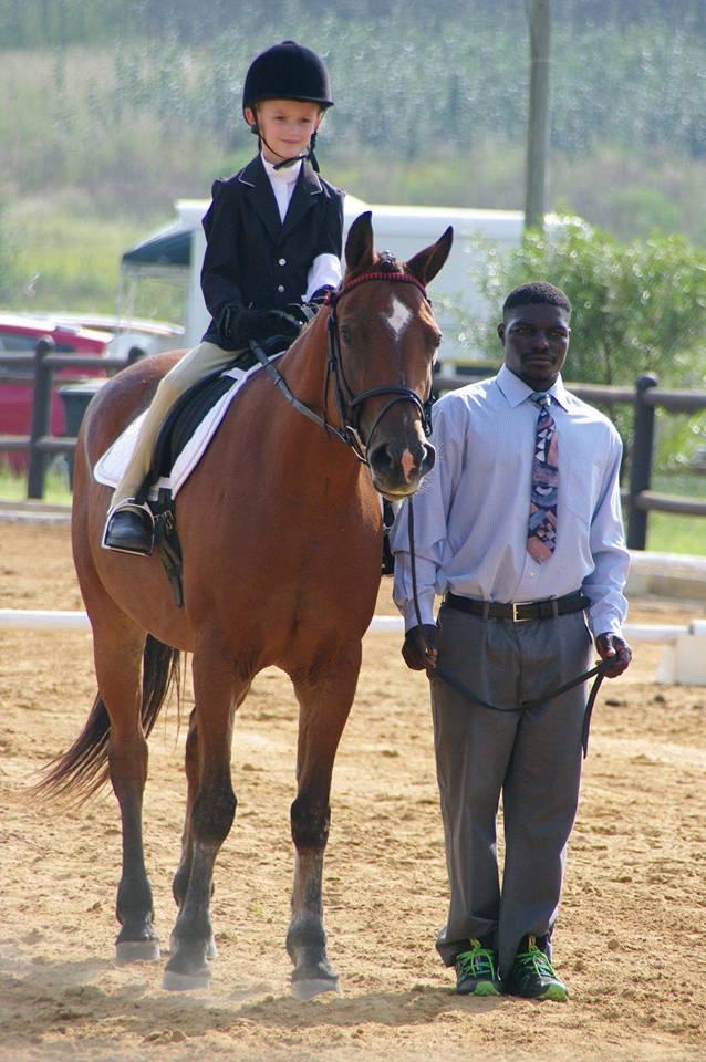 A young rider on a chestnut pony at a show